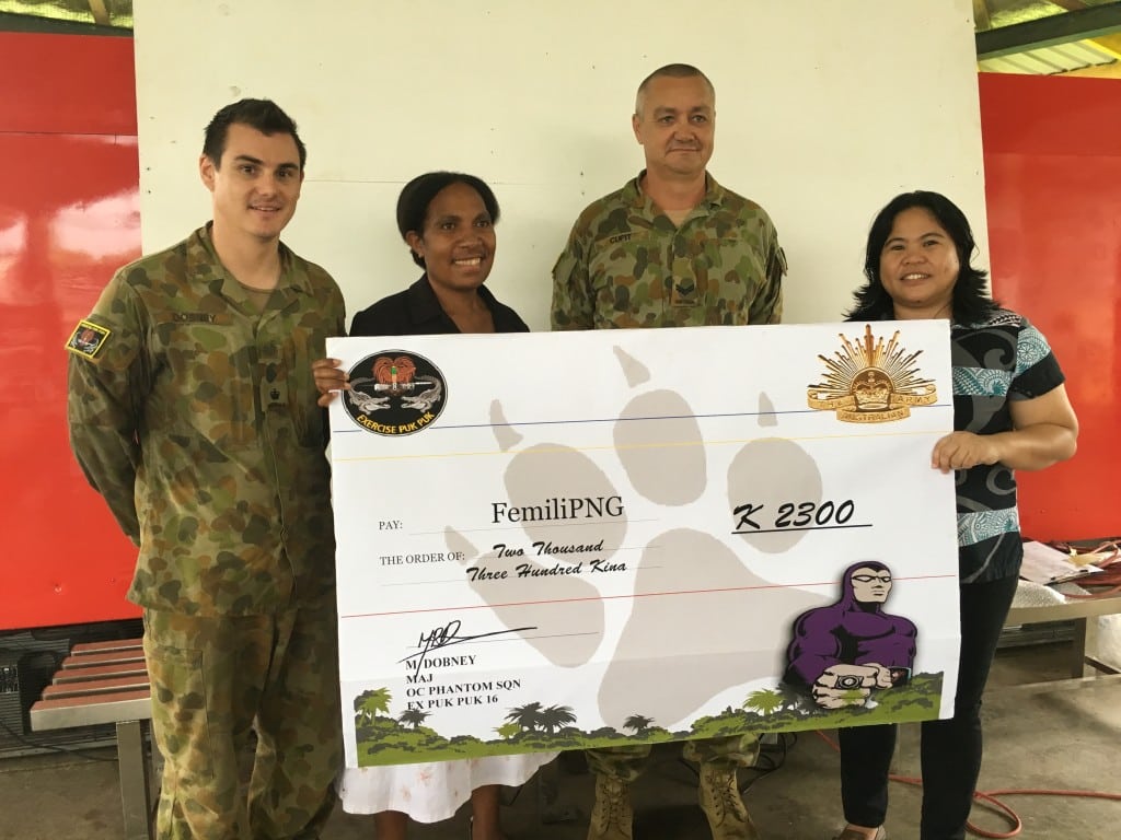 Major Downey and Corporal Cupit handover the cheque to Femili PNG's Denga Ilave and Daisy Plana