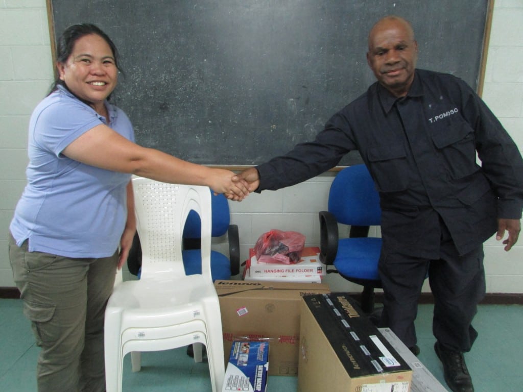 Superintendent Timothy Pomoso shaking hands with Femili PNG CEO Daisy Plana, over the donated items to the police department.